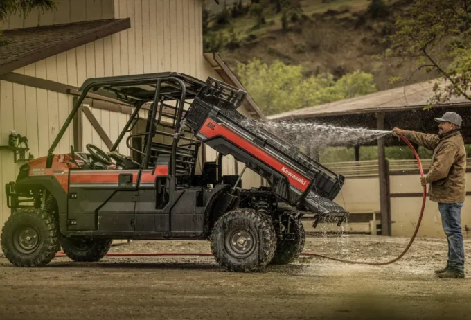 man washing the cargo bay of a Kawasaki Mule